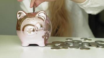 Girl puts money in a pink piggy bank video