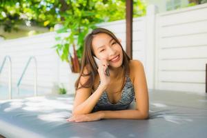Portrait beautiful young asian woman happy smile talk mobile phone around swimming pool photo