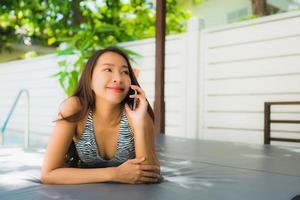 retrato, hermoso, joven, mujer asiática, feliz, sonrisa, hablar, teléfono móvil, alrededor, piscina foto