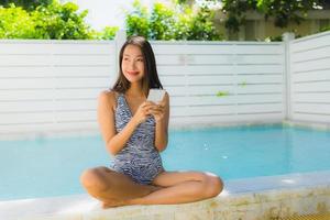 Portrait beautiful young asian woman happy smile talk mobile phone around swimming pool photo