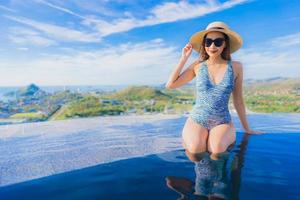 Portrait beautiful young asian woman smile happy relax around swimming pool in hotel resort with sea and ocean view photo