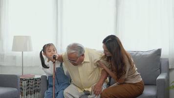 Asian family, Daughter and granddaughter take care support grandfather who is suffering from knee pain Got walking outside to take a walk And grandpa with a stick, elderly health care concept video