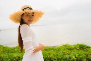 Portrait beautiful asian woman wear hat with smile happy leisure on the beach and sea in holiday vacation photo