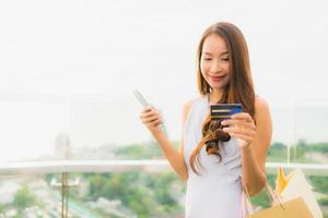Portrait beautiful young asian woman happy and smile with credit card and mobile or smart phone and shopping bag photo