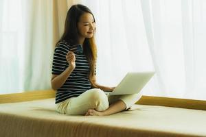 Portrait beautiful young asian woman using computer notebook or laptop with credit card for shopping photo