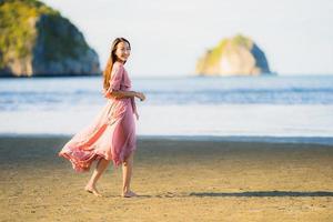 retrato, joven, hermoso, mujer asiática, caminar, sonrisa, y, feliz, en, el, playa, mar y océano foto