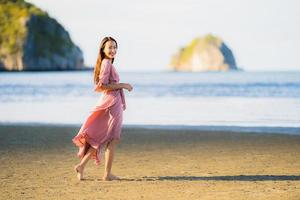 retrato, joven, hermoso, mujer asiática, caminar, sonrisa, y, feliz, en, el, playa, mar y océano foto