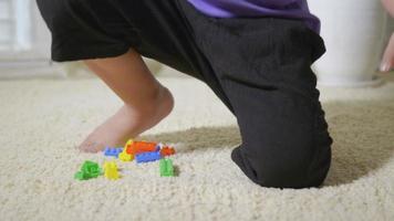glücklicher asiatischer Junge im Vorschulalter gießt und spielt Plastikspielzeugblöcke, die zu Hause bleiben. lustiger kleiner Kinderdump bunter Block, pädagogisches Konstruktionsspielkonzept video