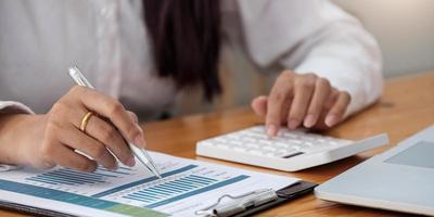 Woman with financial report and calculator. Woman using calculator to calculate report at the table in office photo