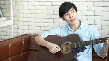 jovem asiático tocando violão e cantando em casa video