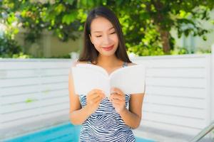 retrato, hermoso, joven, mujer asiática, feliz, sonrisa, con, libro de lectura, alrededor, piscina foto