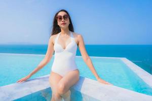 Portrait beautiful young asian woman happy smile relax in swimming pool for travel vacation photo