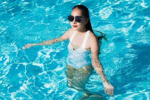 Beautiful young asian woman happy and smile in swimming pool for relax travel and vacation photo