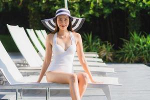 retrato, hermoso, joven, mujer asiática, feliz, sonrisa, y, relajante, alrededor, piscina, en, hotel, resort foto