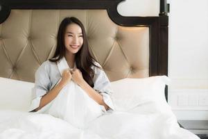 Portrait beautiful young asian woman wake up with happy and smile on bed in bedroom interior photo