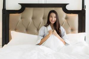 Portrait beautiful young asian woman wake up with happy and smile on bed in bedroom interior photo