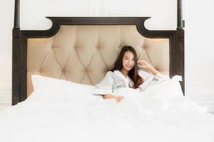 Portrait beautiful young asian woman wake up with happy and smile on bed in bedroom interior photo