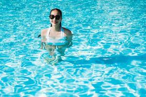 Hermosa joven asiática feliz y sonrisa en la piscina para relajarse viajes y vacaciones foto