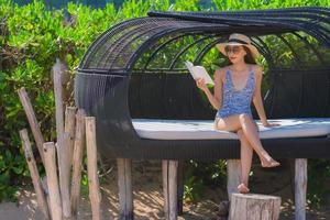 Portrait beautiful young asian woman reading book with happy smile relax in lounge bed chair on the beach sea ocean for leisure photo