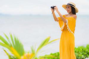 Portrait beautiful asian woman wear hat with smile happy leisure in take a photo on the beach and sea in holiday vacation