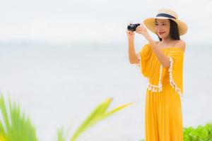 Portrait beautiful asian woman wear hat with smile happy leisure in take a photo on the beach and sea in holiday vacation