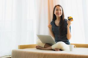 Portrait beautiful young asian woman using computer notebook or laptop with credit card for shopping photo