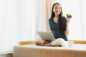 Retrato joven y bella mujer asiática con ordenador portátil o portátil con tarjeta de crédito para ir de compras foto