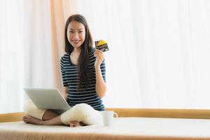 Retrato joven y bella mujer asiática con ordenador portátil o portátil con tarjeta de crédito para ir de compras foto