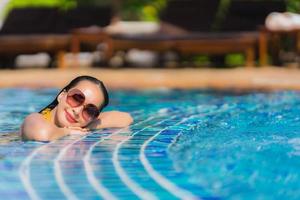 Portrait beautiful young asian woman leisure relax smile and happy around swimming pool in hotel resort photo