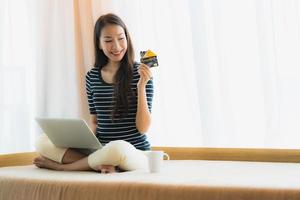 Portrait beautiful young asian woman using computer notebook or laptop with credit card for shopping photo