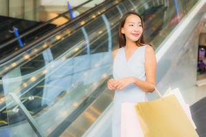 Retrato hermosa joven asiática feliz y sonrisa con bolsa de compras de los grandes almacenes foto