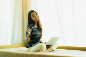 Retrato joven y bella mujer asiática con ordenador portátil o portátil con tarjeta de crédito para ir de compras foto