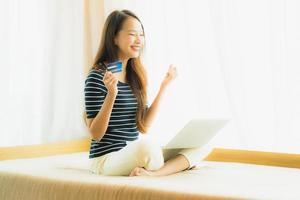 Retrato joven y bella mujer asiática con ordenador portátil o portátil con tarjeta de crédito para ir de compras foto