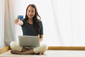 Portrait beautiful young asian woman using computer notebook or laptop with credit card for shopping photo