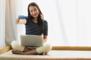 Retrato joven y bella mujer asiática con ordenador portátil o portátil con tarjeta de crédito para ir de compras foto