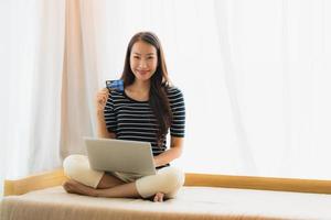 Portrait beautiful young asian woman using computer notebook or laptop with credit card for shopping photo