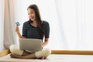 Portrait beautiful young asian woman using computer notebook or laptop with credit card for shopping photo