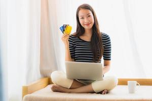 Retrato joven y bella mujer asiática con ordenador portátil o portátil con tarjeta de crédito para ir de compras foto