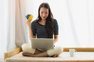 Portrait beautiful young asian woman using computer notebook or laptop with credit card for shopping photo