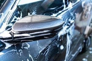 Espejo lateral de coche de primer plano con espuma de lavado de coches foto