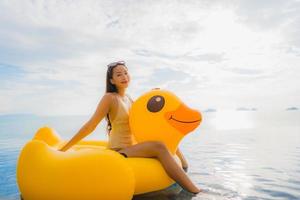 Portrait young asian woman on inflatable float yellow duck around outdoor swimming pool in hotel and resort photo