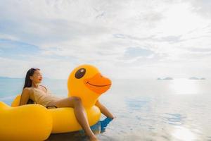 Portrait young asian woman on inflatable float yellow duck around outdoor swimming pool in hotel and resort photo