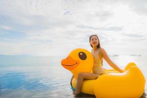 Portrait young asian woman on inflatable float yellow duck around outdoor swimming pool in hotel and resort photo