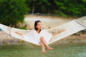 Portrait beautiful young asian woman sitting on hammock around sea beach ocean for relax photo