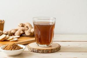 Hot and sweet ginger juice glass with ginger roots - Healthy drink style photo