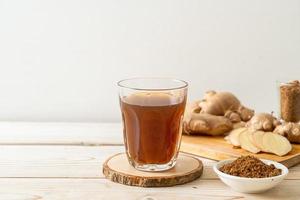 Hot and sweet ginger juice glass with ginger roots - Healthy drink style photo