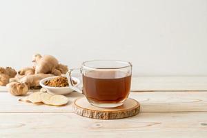 Hot and sweet ginger juice glass with ginger roots - Healthy drink style photo