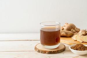 Hot and sweet ginger juice glass with ginger roots - Healthy drink style photo