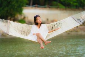 Portrait beautiful young asian woman sitting on hammock around sea beach ocean for relax photo