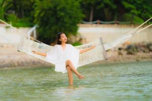 Portrait beautiful young asian woman sitting on hammock around sea beach ocean for relax photo